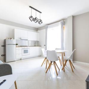 a white kitchen with a table and white chairs at Casa Libeccio in Quartu SantʼElena +6 photos