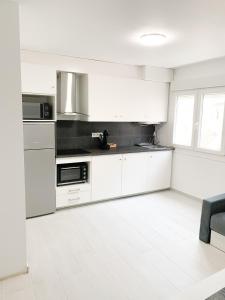 a kitchen with white cabinets and a white tile floor at Estudio 2 Minutos De La Playa in Portonovo
