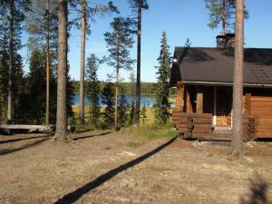 a log cabin with a lake in the background at Ukonloma Aimola in Rovaniemi