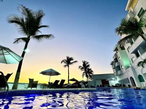 a swimming pool with palm trees and a building at Espectacular Apto remodelado, de lujo y a pie de Playa con vista al mar in Manzanillo