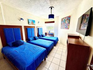 three beds in a room with blue sheets at Espectacular Apto a pie de Playa con vista al mar in Manzanillo