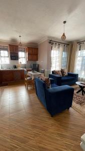 a living room with two blue couches and a kitchen at BAZY SUITEs in Kampala