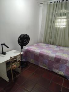 a bedroom with a bed and a desk with a lamp at Lar da Elis in Riacho Fundo +3 photos