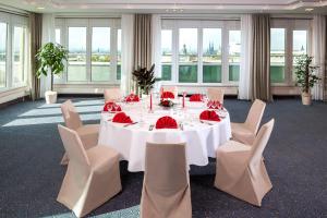 une salle à manger avec une table et des chaises blanches dans l'établissement Dorint Charlottenhof Halle (Saale), à Halle-sur-Saale