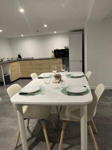 a white table with chairs and wine glasses on it at Les chambre de Marie studio Rez de chaussé in Didenheim