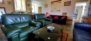 a living room with green leather furniture and a table at L' Anpeg, gîte dans le Cotentin jusqu'à 8 personnes in Besneville