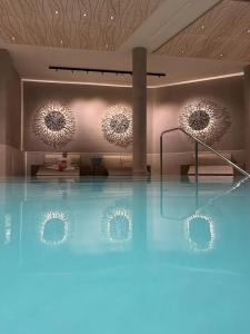 a room with a swimming pool with two mirrors at SlowDown Bottsand Hotel und Spa in Wendtorf