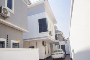 a white house with a car parked in a driveway at Two Bedroom Apartment Magodo Lagos in Magodo