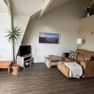 a living room with a couch and a tv at Herenstraat 55 in Den Hoorn