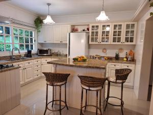 a kitchen with white cabinets and a island with bar stools at A Casa Serena in Morro Reuter
