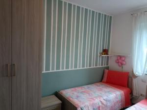 a small bedroom with a bed and a striped wall at Casa bella vista Emma lago Como in Vercana