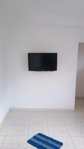 un mur blanc avec une télévision et deux tapis bleus au sol dans l'établissement Apartamento Brisa 201, à Pedra de Guaratiba