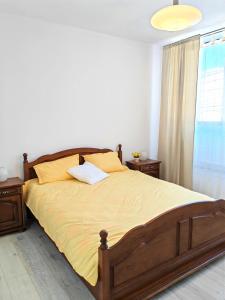 een slaapkamer met een bed met gele lakens en een raam bij Central Apartments Madona in Craiova