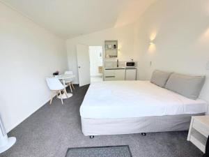 ロトルアにあるUnit 1, Fenton Summer Lodgeのベッドルーム(白いベッド1台、テーブル付)