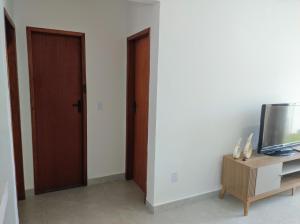 カボ・フリオにあるOndas do Peróの2つのドアとテーブル上のテレビが備わる客室です。 +13枚の写真