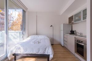 a small white bedroom with a bed and a window at Recoleta, cómodo, cerca de todo, WiFi, Balcón in Buenos Aires