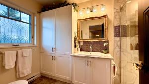 Un baño blanco con lavabo y espejo. en Seagull Studio Vacation Suite, en Sooke