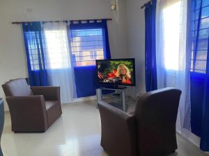 a living room with a tv and chairs and blue curtains at Apartamentos Anahí in Villa Parque Siquiman