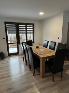 a dining room with a wooden table and black chairs at Apartmán Borák in Velké Karlovice