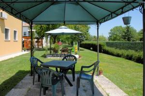 una mesa y sillas bajo una sombrilla verde en Agriturismo Il Melograno, en Tessera