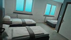 three beds in a room with two windows at Hotel Delisa in Berlin