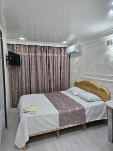 una camera con un grande letto e una tenda di Гостиничный номер 3 a Shymkent