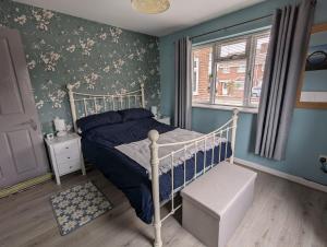 a bedroom with a bed with blue walls and a window at The Sty in Swindon