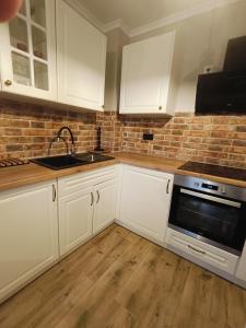 a kitchen with white cabinets and a brick wall at Apartament osiedle Natura Wieliszew in Wieliszew