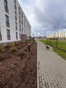 a brick sidewalk next to a building next to a field at Apartament osiedle Natura Wieliszew in Wieliszew