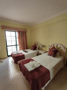 a hotel room with two beds and a window at Dunas Pool View by MyLokals in Alvor
