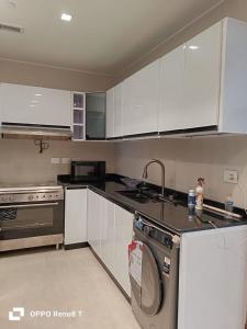 a kitchen with white cabinets and a washing machine at luxury apartment three bedrooms three bathrooms in 6th Of October
