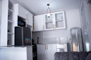 a kitchen with white cabinets and a black refrigerator at Luxe cozy home in Dar es Salaam +2 photos