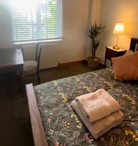 a bedroom with a bed with a towel on it at Wheel Corner Cottage in Kingsteignton +11 photos