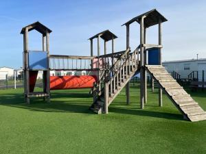 a playground with a red slide on the grass at Dans le vent in Middelkerke