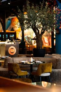 un ristorante con tavoli, sedie e un albero di Boutiquehotel The Church ad Arnhem