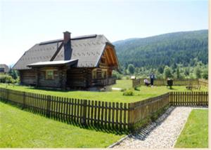 ein Holzhaus mit einem Zaun davor in der Unterkunft Log Home in Mauterndorf