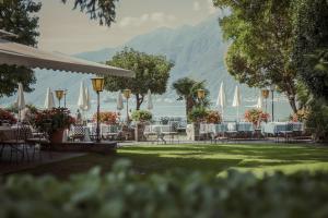 um grupo de mesas e cadeiras com veleiros na água em Romantik Hotel Castello Seeschloss em Ascona