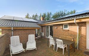 a patio with white chairs and a table and a building at 5 Bedroom Nice Home In Blåvand in Blåvand +18 photos