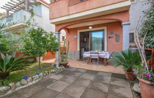 1 Bedroom Lovely Home In Viddalba في Viddalba: منزل مع طاولة في ساحة مليئة بالنباتات