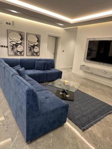 a living room with a blue couch and a tv at Jamal Royal Apartments in Al Madinah