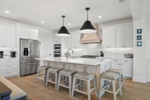 a kitchen with white cabinets and a large island with bar stools at Beachside Beauty at Surfview Paradise in Palm Coast +67 photos