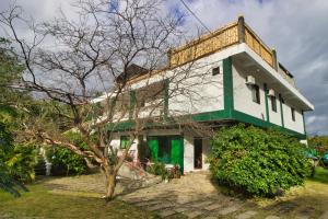 a white and green building with a tree in front of it at Casa Luntian Lodge and Cafe in Puerto Galera
