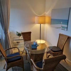 a dining room with a glass table and chairs at Fewo Muschelgetuschel im Prinz Hamlet - Pool und direkte Strandlage in Pelzerhaken +18 photos