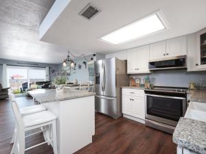 Una cocina con gabinetes blancos y un refrigerador de acero inoxidable. en Starboard Light 7, en Ormond Beach