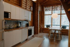 a kitchen with white cabinets and a table in front of a window at Kiilopää Lodge Lapland Cabin in Kakslauttanen +46 photos