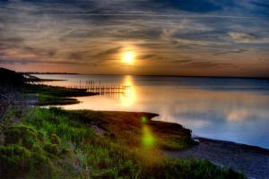 um pôr-do-sol sobre um corpo de água com um cais em The Inn on Pamlico Sound em Buxton