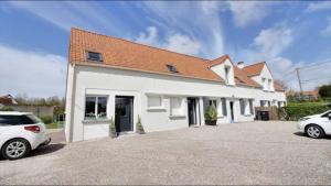 ein weißes Haus mit zwei Autos, die in einer Einfahrt geparkt sind in der Unterkunft Appartement 3 chambres 6 pers in Saint-Josse