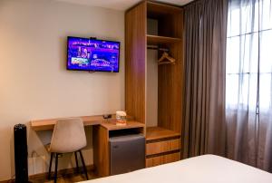 um quarto de hotel com uma secretária e uma televisão na parede em SkyHub em Bogotá