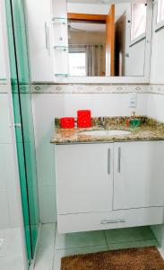 un bagno con lavandino e specchio di 3 quartos a 280m da praia c roupa de cama - Sacada com Churrasqueira - climatizado - 10 min a pé da passarela do Ribeiro e acesso a Praia de Bombinhas - 5 min a pé de supermercados - Até 8 pessoas, ideal p famílias, grupos, crianças a Bombas