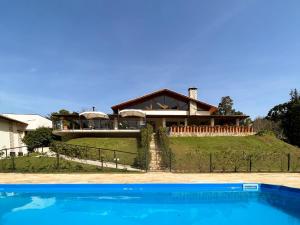 a house on top of a hill with a swimming pool at Gardenian Lodge in São Roque